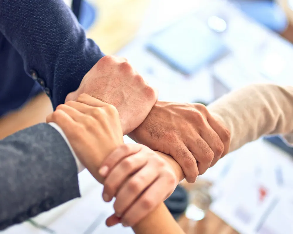 Four hands placed on top of each other – teamwork
